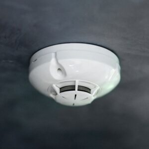 white carbon monoxide detector on a black ceiling