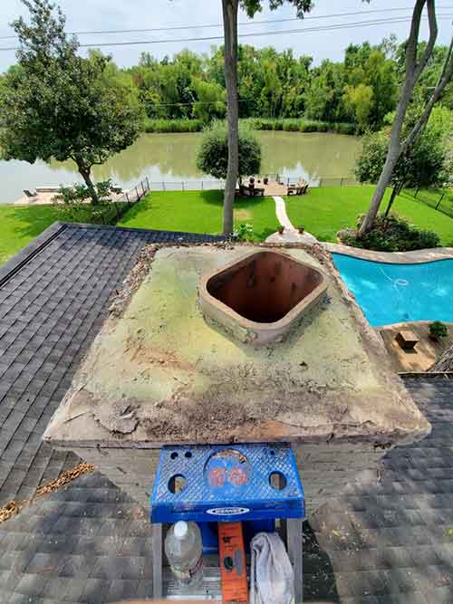 Crumbling chimney crown with mold. Pool and lake in background.