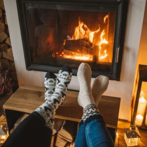 two people's feet with cozy socks on them propped up by a fireplace