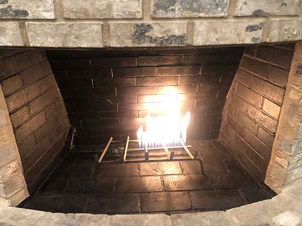 Facelifts-gas fireplace update with black chimney box surrounded by light colored brick and gas fire no logs
