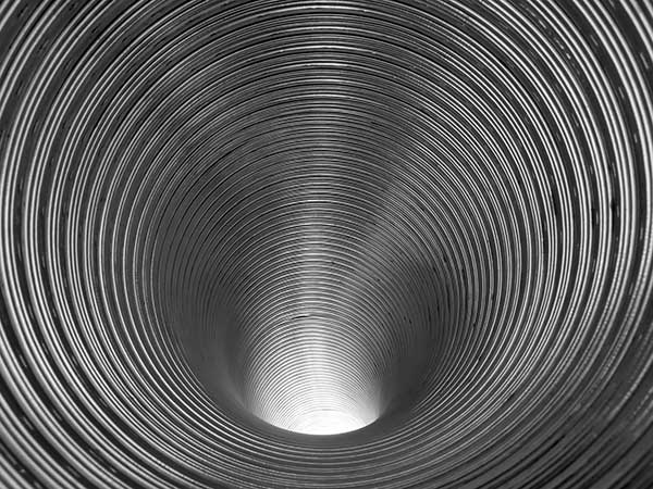 Looking down interior of a ribbed stainless steel chimney liner.