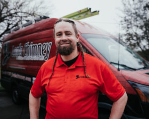 Courtney Taylor Technician with red shirt and log along with company truck with logo in the background.- Houston TX - Lords Chimney