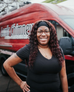 Kerrhonda King Technician in black blouse with long dark hair and glasses.  Company truck in background with logo.- Houston TX - Lords Chimney