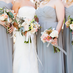 a bride standing next to her bridesmaids dressed in grey