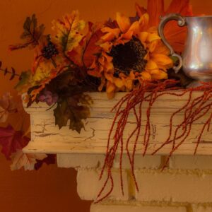 a white fireplace mantel with fall-themed decor on it